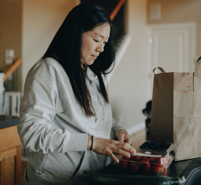 A woman looking down while shopping, holding a paper bag