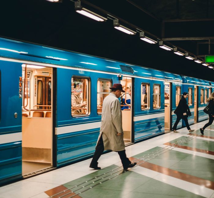 A blue Stockholm metro train at a station platform with a passenger boarding