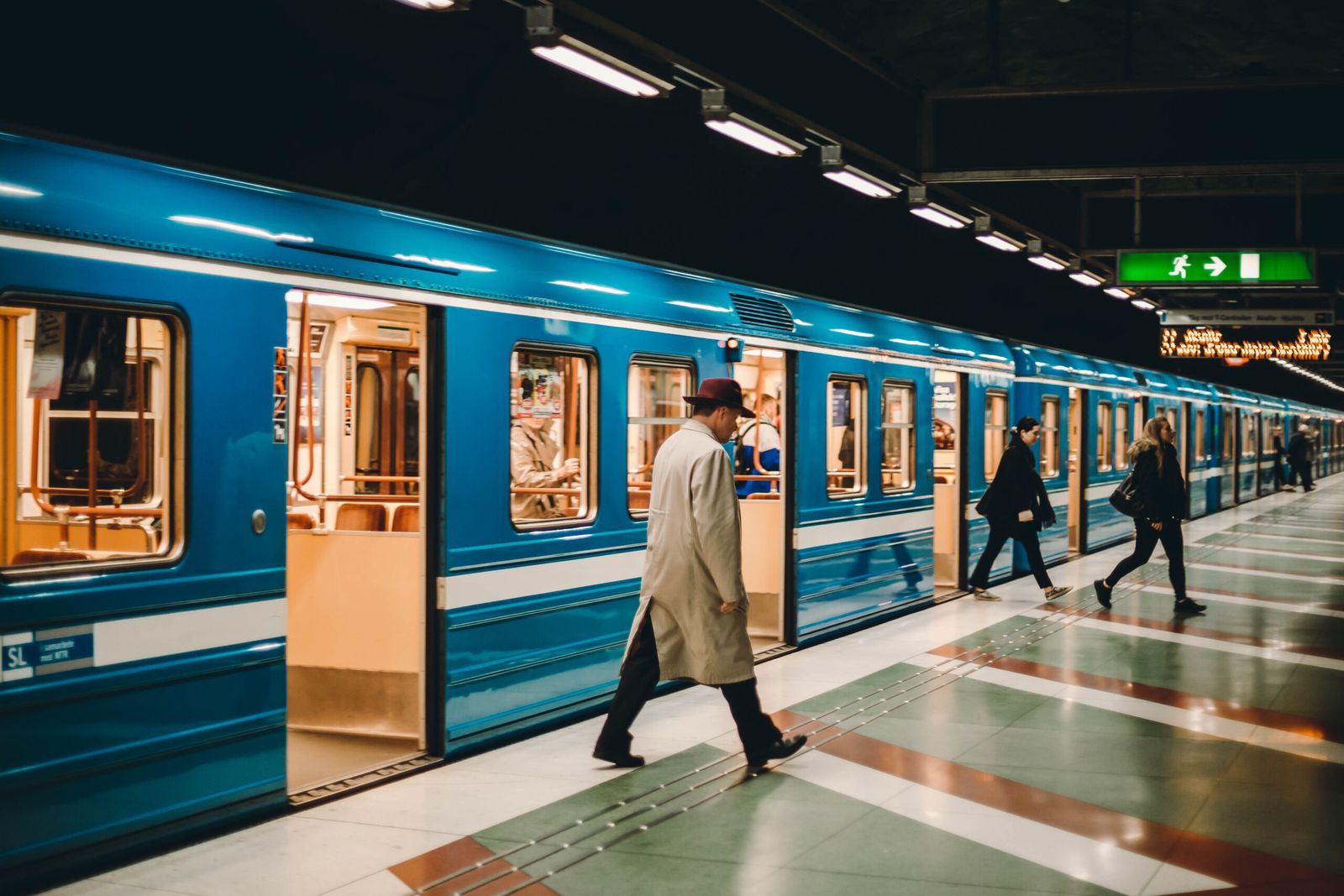 A blue Stockholm metro train at a station platform with a passenger boarding
